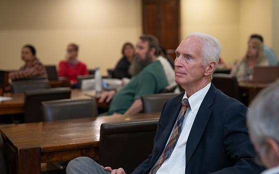 close up of faculty member with other out of focus in the background listening to speaker