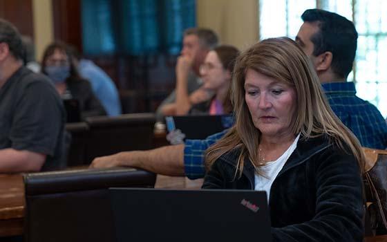 faculty member taking notes on computer during presentation