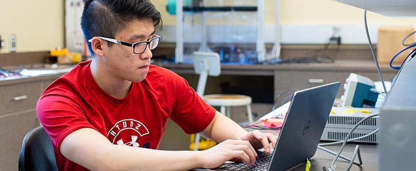 Male student working on laptop in lab.