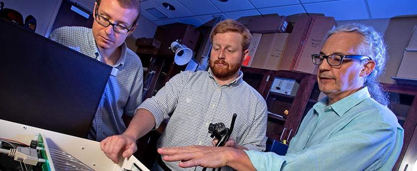 Thomas Rich, Ph.D., professor of pharmacology at the University of South Alabama College of Medicine (far left), and Silas Leavesley, Ph.D., associate professor of chemical and bimolecular engineering at USA (far right), work in an engineering lab with Craig Browning, a doctoral student in the science systems engineering program at USA.